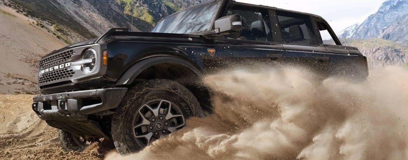 A black 2025 Ford Bronco Badlands is off-roading on a sandy desert area.