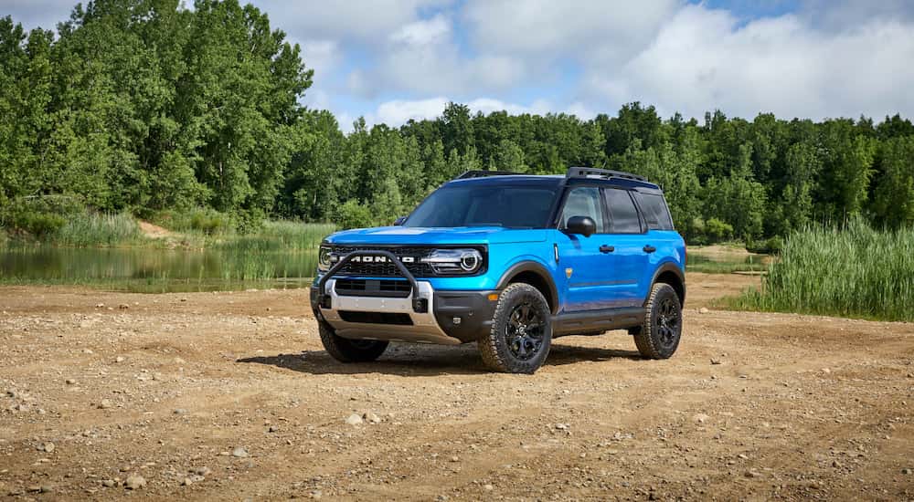 A blue 2025 Ford Bronco Sport Badlands Sasquatch parked off-road near water.