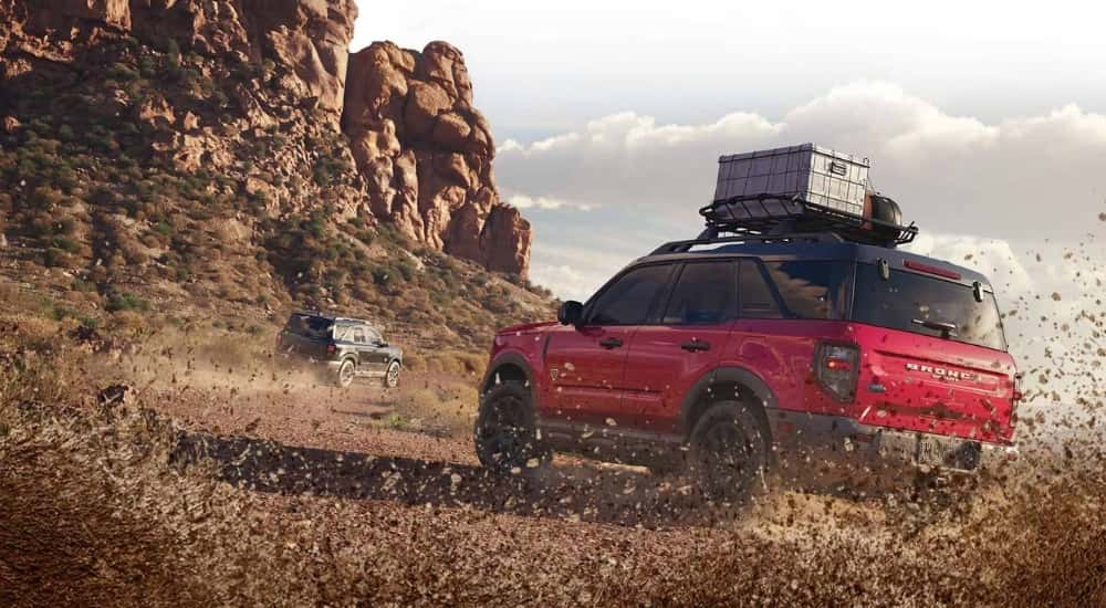 Rear view of a red 2025 Ford Bronco Sport Sasquatch kicking up mud while off-roading.
