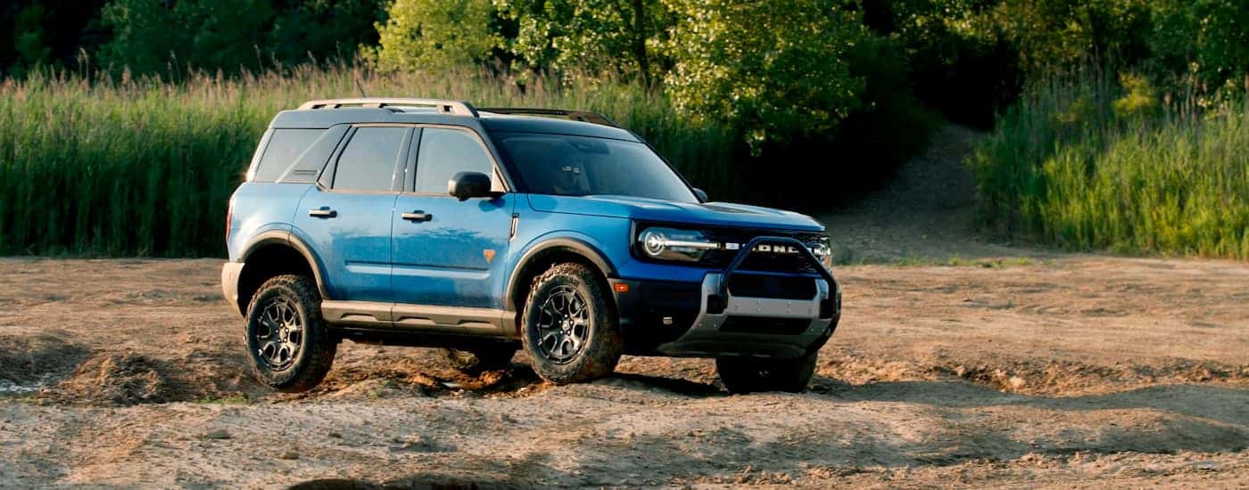 A blue 2025 Ford Bronco Sport Badlands is driving over a dirt path.