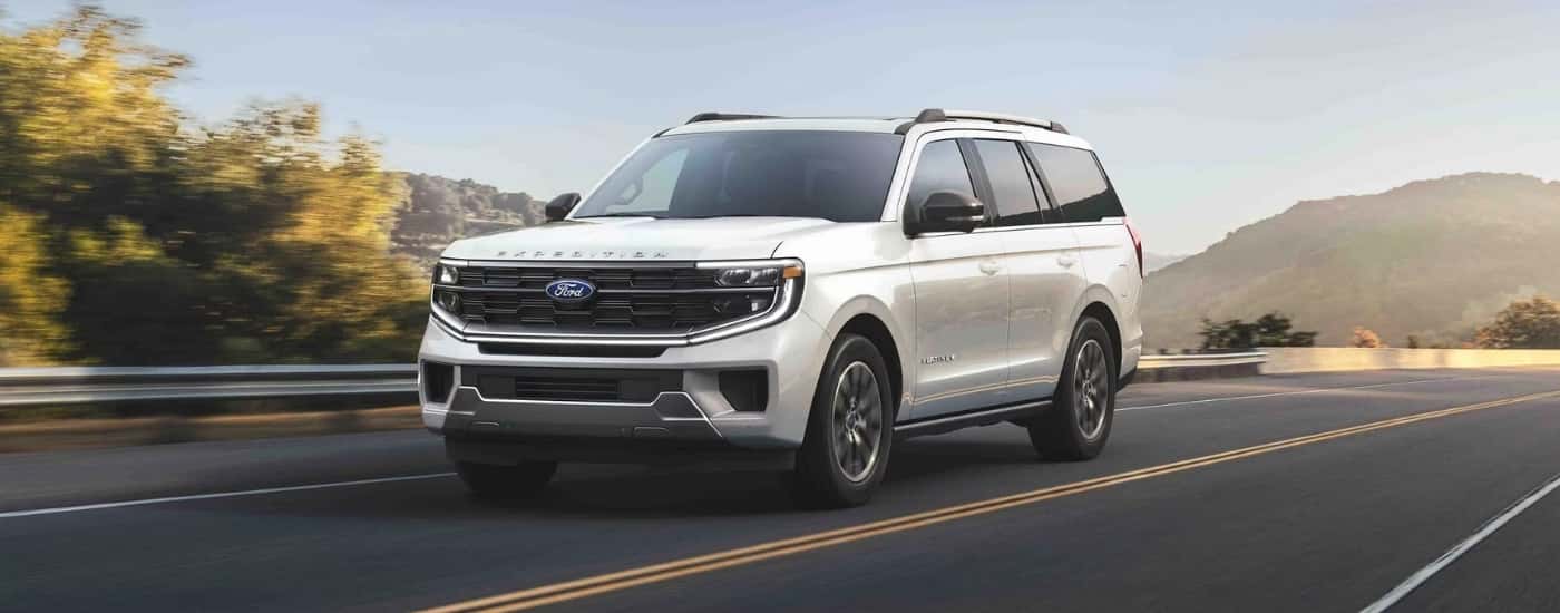 A white 2025 Ford Expedition Platinum is driving on an open highway.