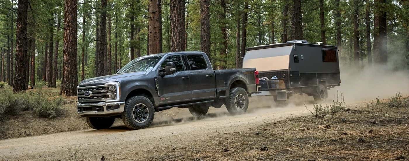 A grey 2025 Ford F-250 Lariat Tremor is shown towing a trailer off-road.