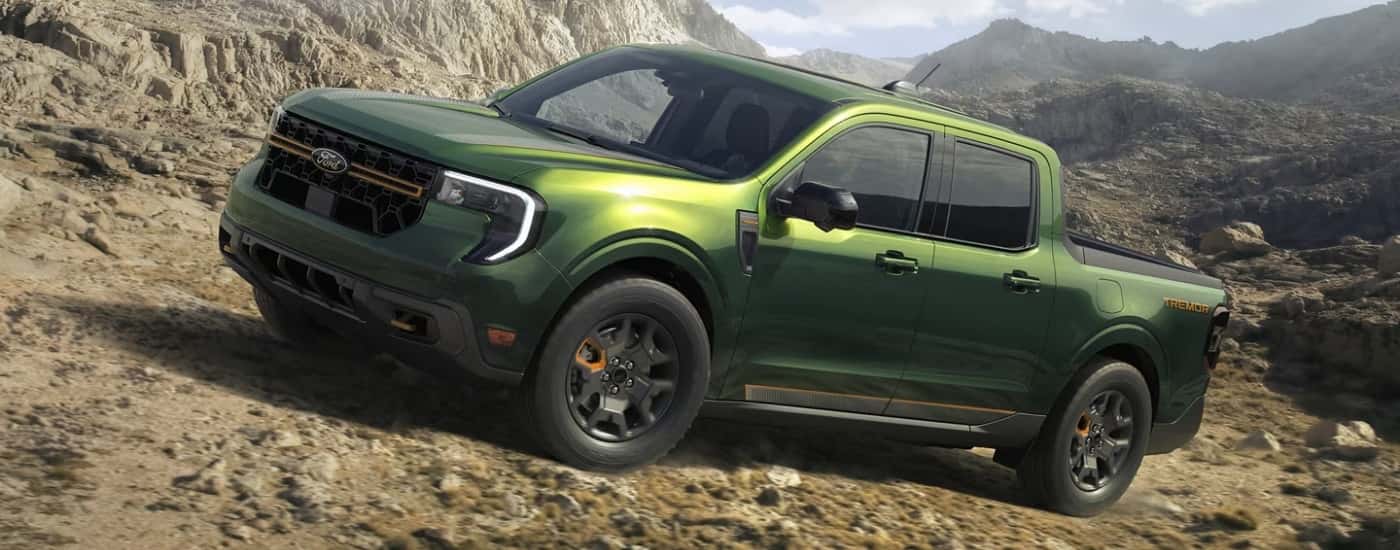 A green 2025 Ford Maverick Tremor is off-roading on a rocky hiking trail.