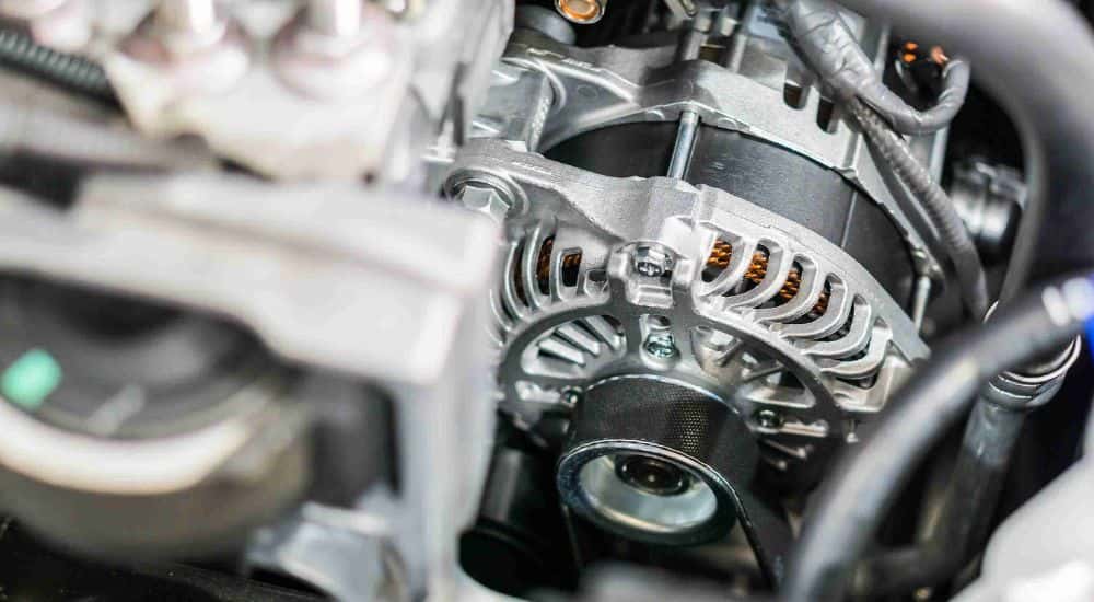 A close up of a mechanic doing an alternator replacement at a repair shop.
