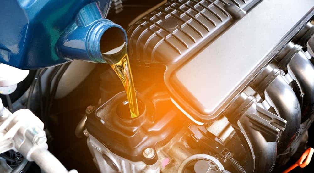 An oil can being poured into an engine.