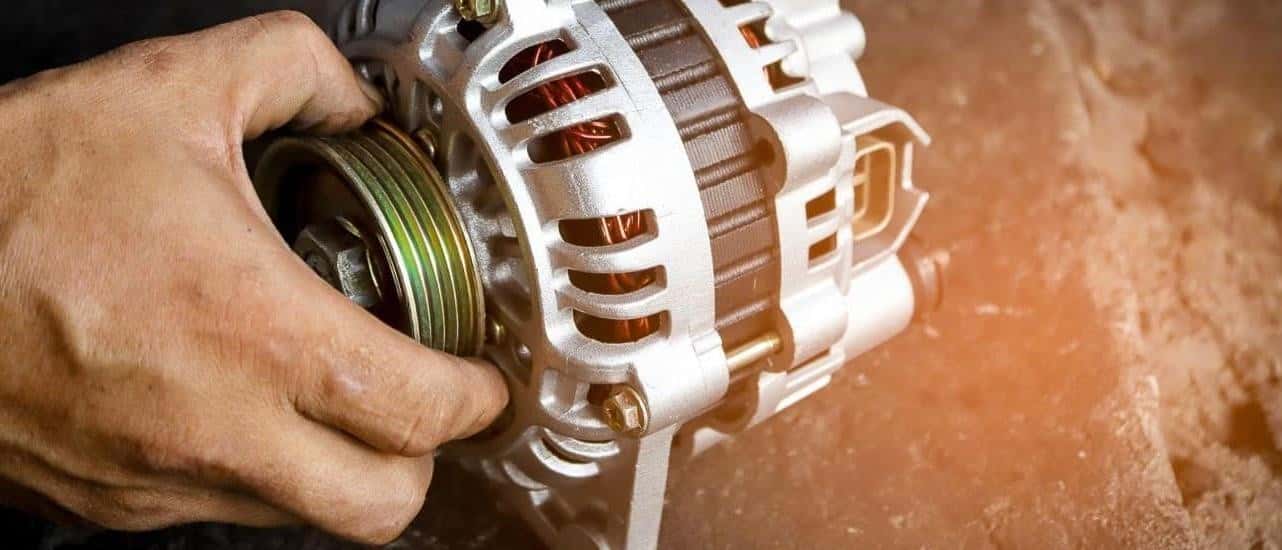 A person is shown holding an alternator.