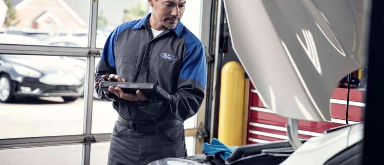 A Ford technician is shown diagnosing a vehicle at an auto repair shop.