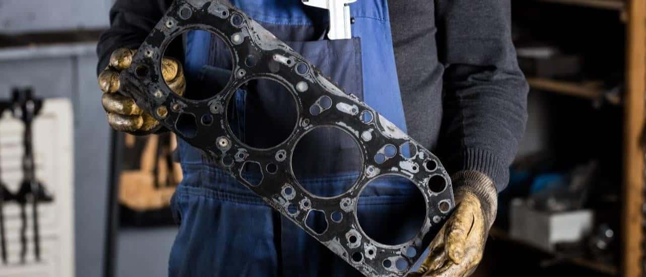 A mechanic is shown holding a head gasket.