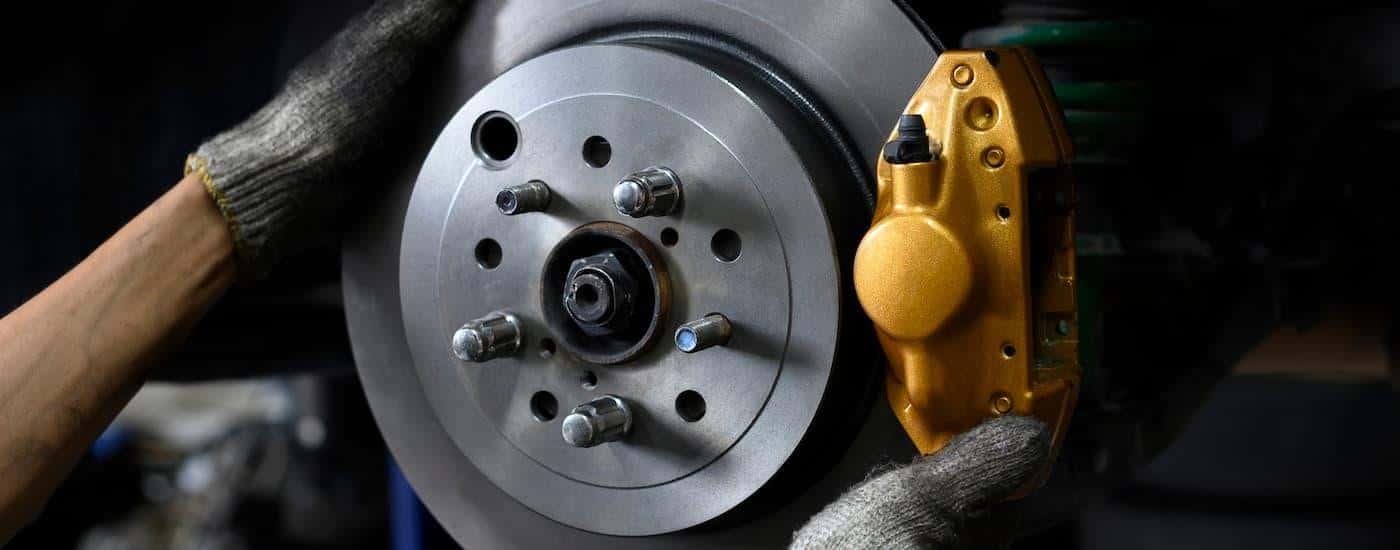 Close-up of a mechanic replacing a rotor and caliper on a vehicle.