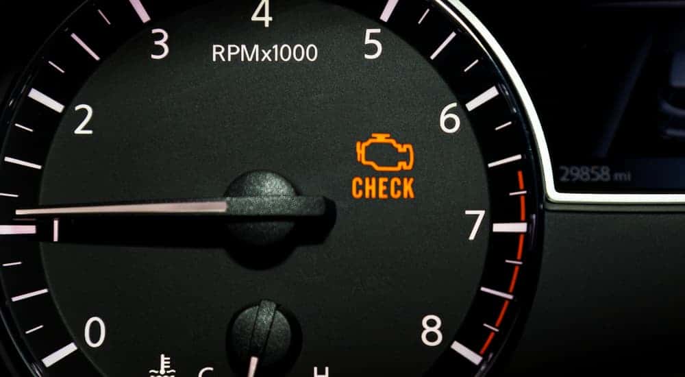 Close-up of an illuminated check engine light on a dashboard.
