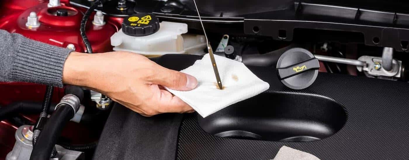 A mechanic is shown checking the oil stick on a vehicle.