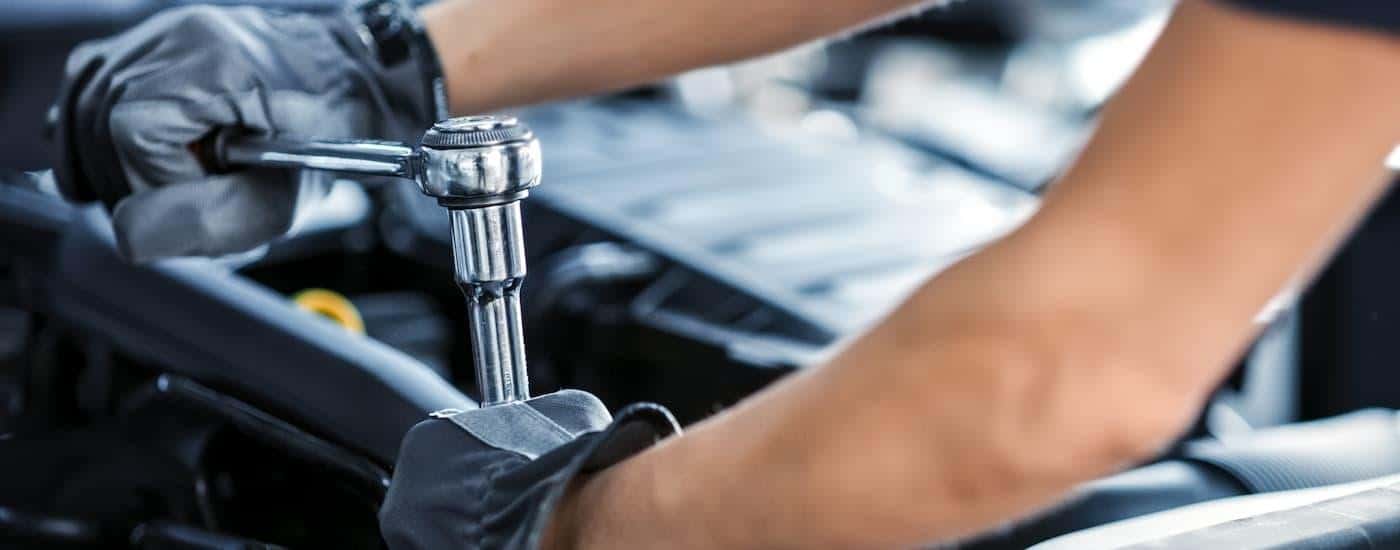 A mechanic is shown working on a vehicle's engine.