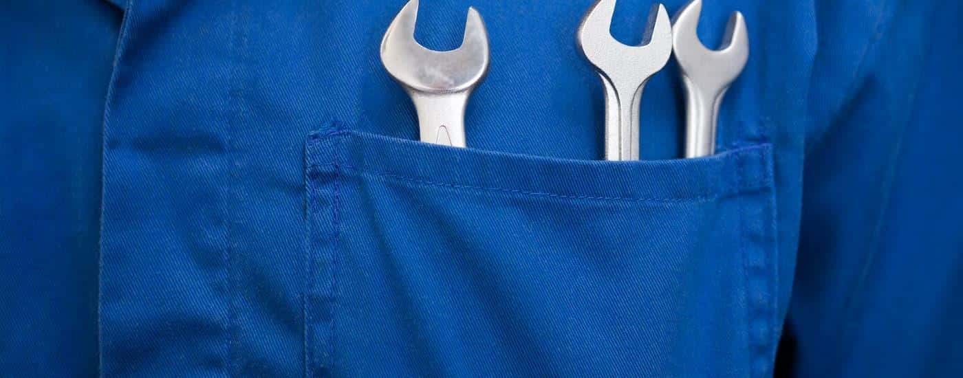 A set of wrenches are shown in a blue jumpsuit pocket.