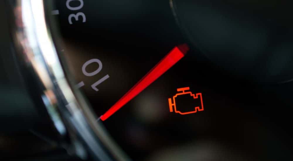 Close-up of a check engine light illuminated on a dashboard.