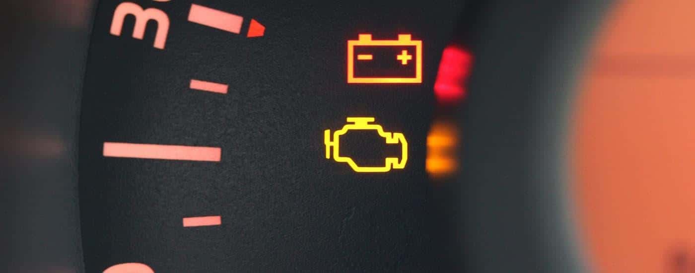 A close up of warning lights on the dashboard of a vehicle are shown illuminated.