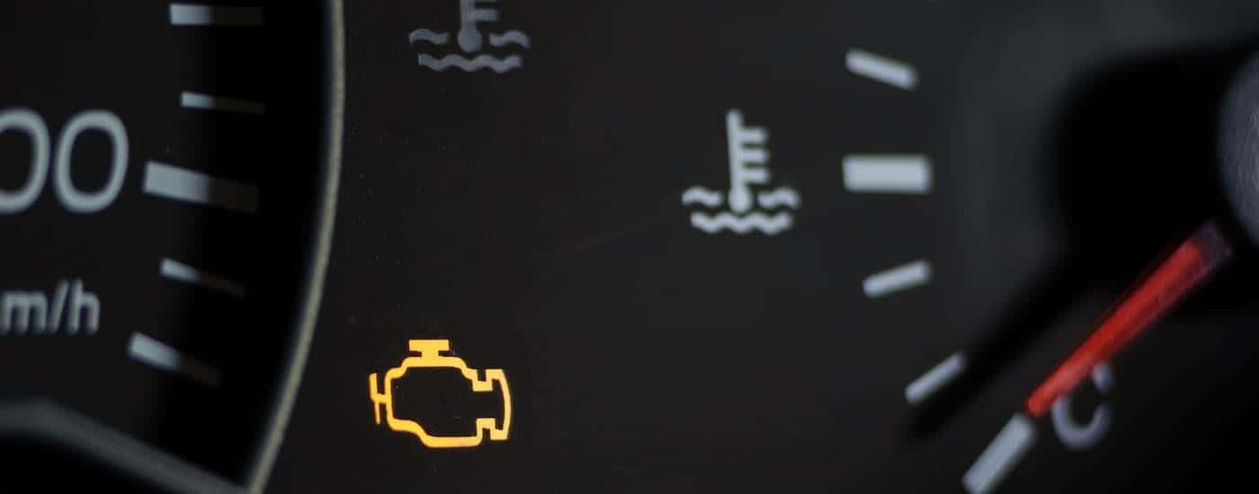 "A close up of a check engine light is shown on a dashboard.
