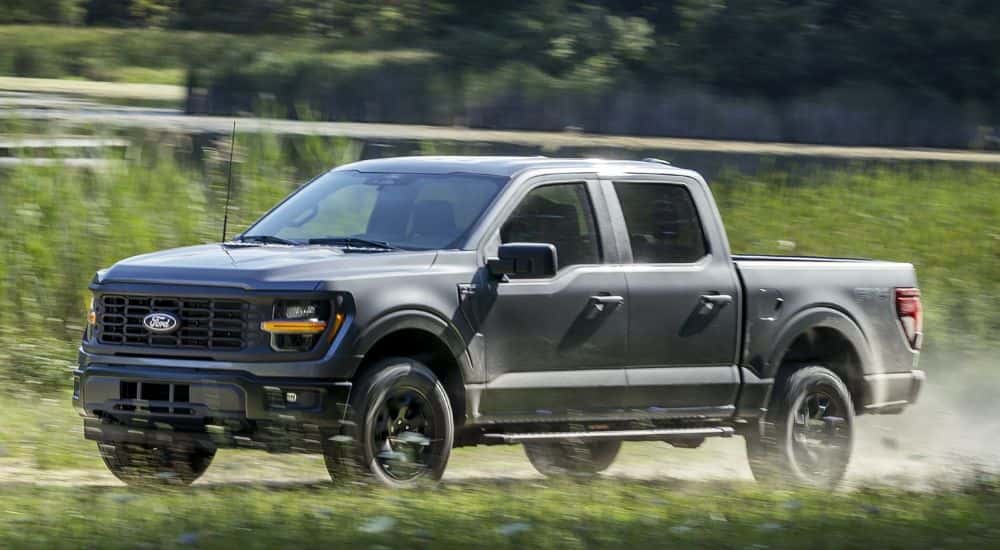 A silver 2024 Ford F-150 STX FX4 driving on a dusty trail.