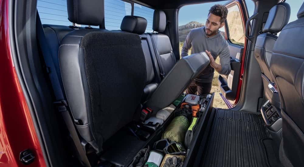 A man accessing the back seat storage in a 2024 Ford F-150.