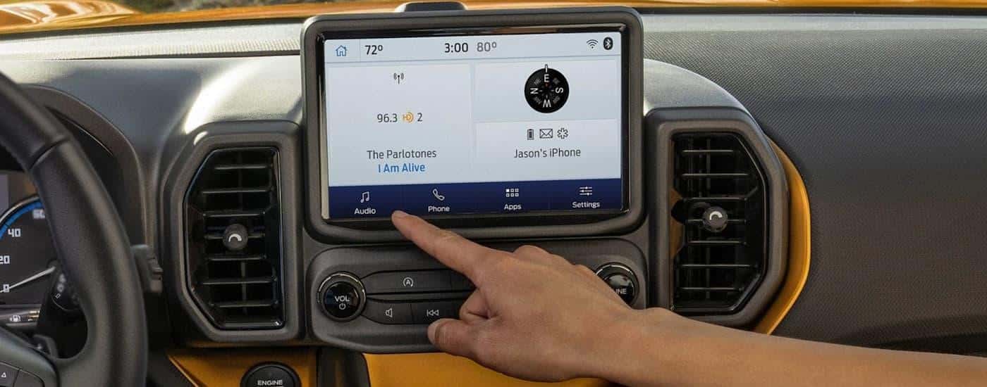 The grey interior of a 2022 Ford Bronco Sport shows the steering wheel and infotainment screen.