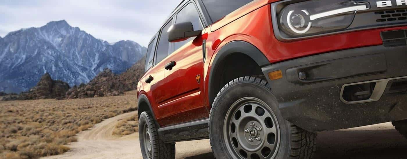 A red 2022 Ford Bronco Sport is shown from the front off-roading in the mountains.