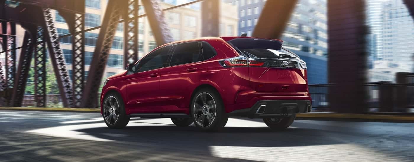 A red 2023 Ford Edge ST is shown from a rear angle driving on a bridge.