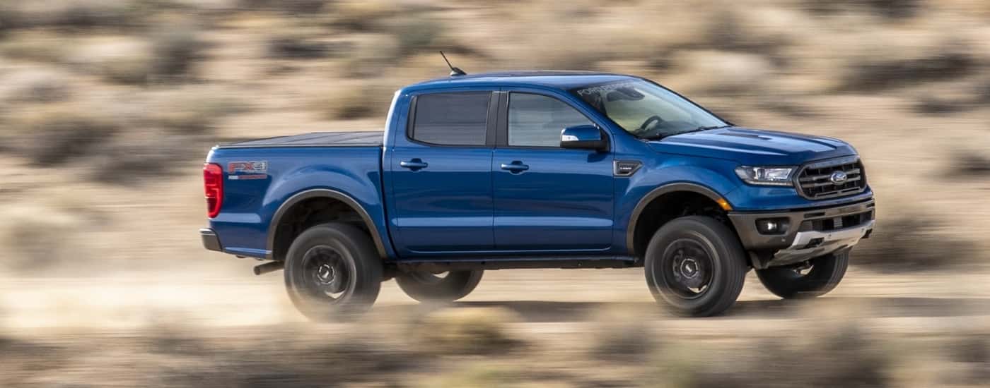 A blue 2021 Ford Ranger is shown from the side driving on a dirt road after leaving a Ford dealer in Loganville.