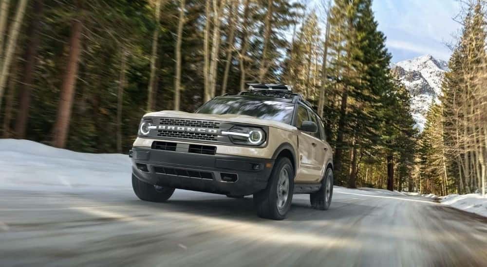 A tan 2024 Ford Bronco Sport Badlands driving through the woods in winter.