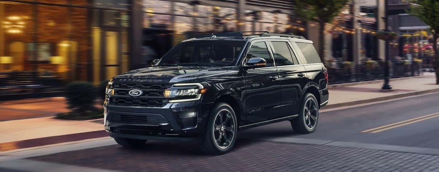 A black 2023 Ford Expedition Stealth is shown driving on a city street.