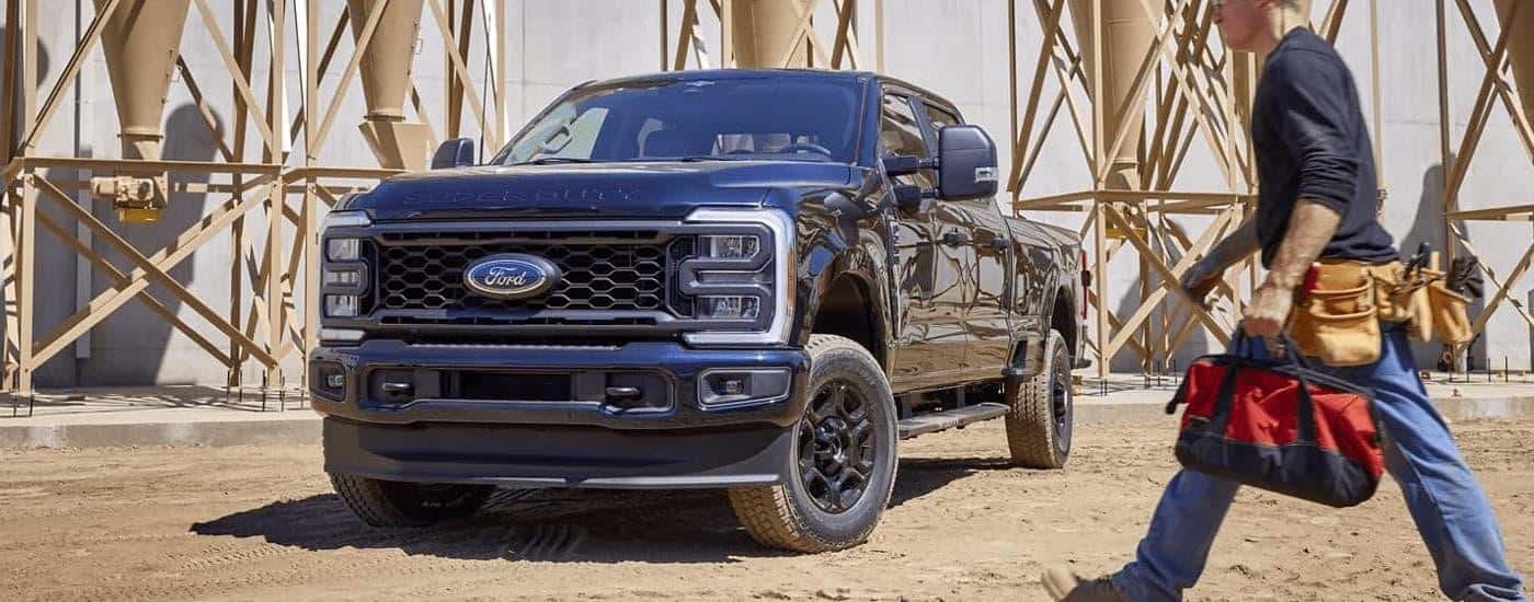 A black 2024 Ford F-250 Super Duty STX is parked at a construction site.