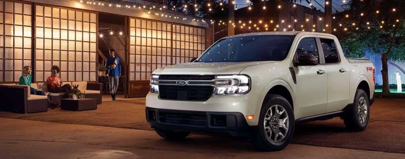A grey 2024 Ford Maverick is parked on a patio with string lights above.