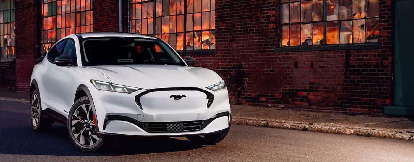 A white 2024 Ford Mustang Mach-E is parked on the side of a street.