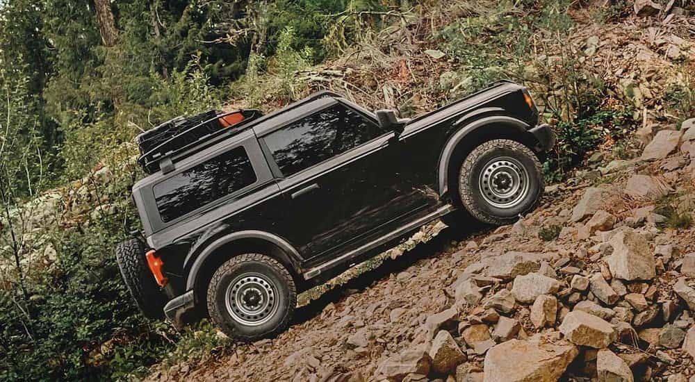 A black 2025 Ford Bronco Base is off-roading on a steep rocky trail.