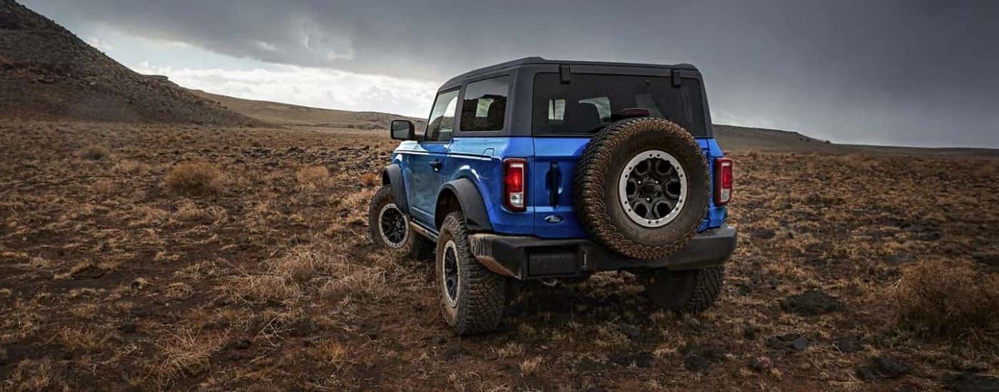 A blue 2023 Ford Bronco Black Diamond Sasquatch is shown from the rear parked on a open field.