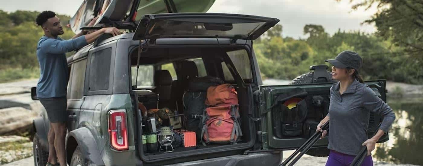 Two people are shown putting camping supplies into the bed of a 2024 Ford Bronco.