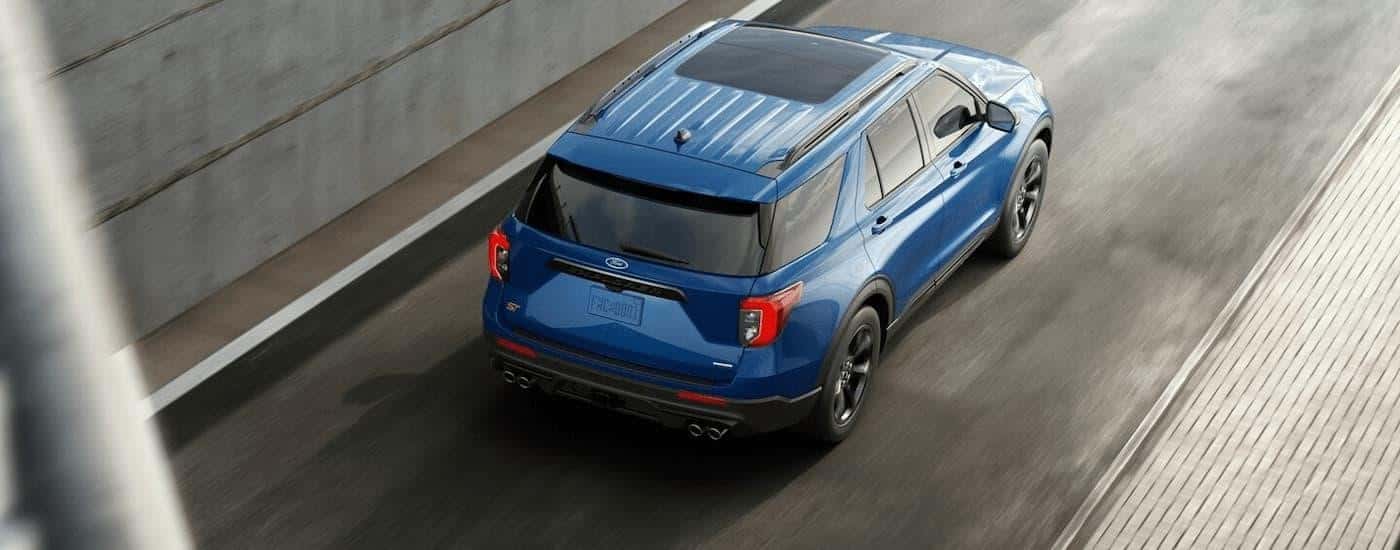 A blue 2023 Ford Explorer ST is shown from a rear angle driving up a highway ramp.