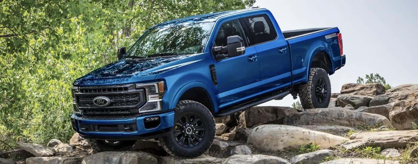 A blue 2022 Ford F-250 is shown off-roading in the mountains after leaving a Ford dealership serving Athens, GA.