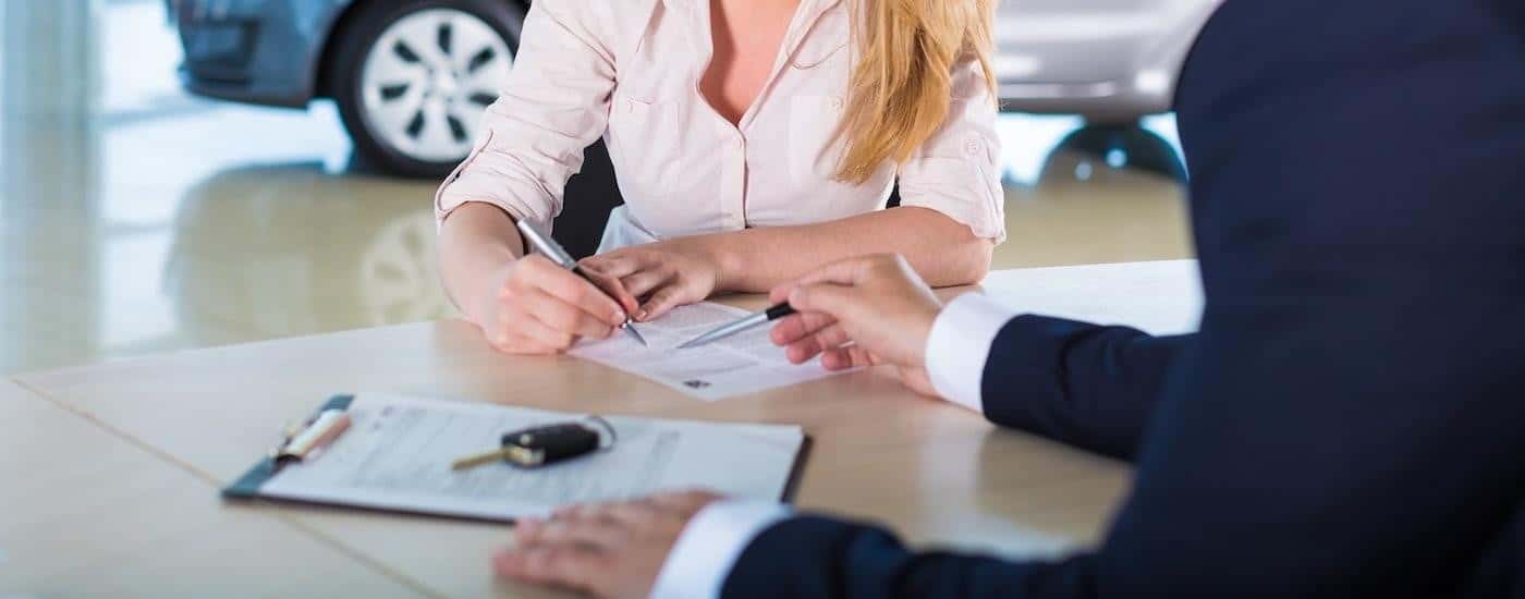 A person is shown filling out paperwork at a Ford dealership.