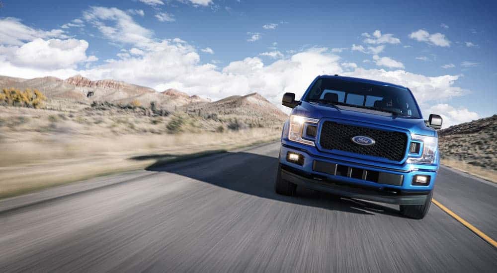Front angle view of a blue 2018 Ford F-150 driving.
