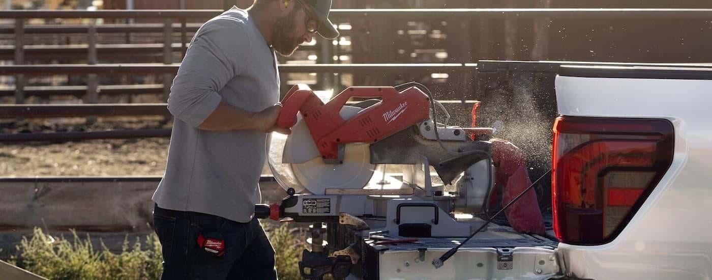 A worker is using the Pro Power feature on a 2025 Ford F-150 to cut wood with an electric table saw.