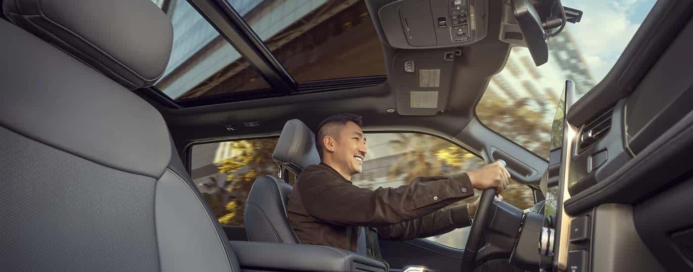 A man is shown driving a 2024 Ford F-150 Lightning for sale during a test drive.