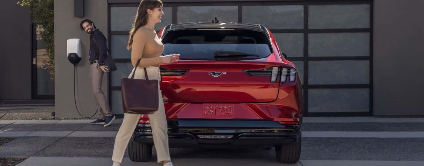 A red 2022 Ford Mustang Mach-E is shown from the rear parked on a driveway.