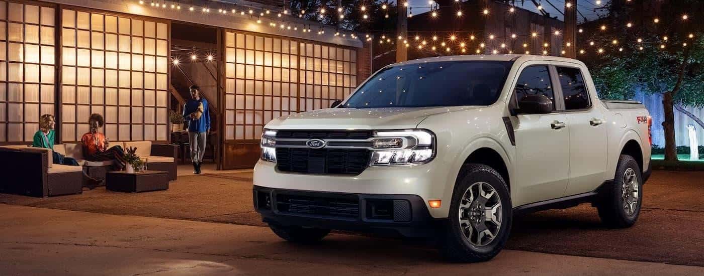 A grey 2024 Ford Maverick for sale parked under patio lights.