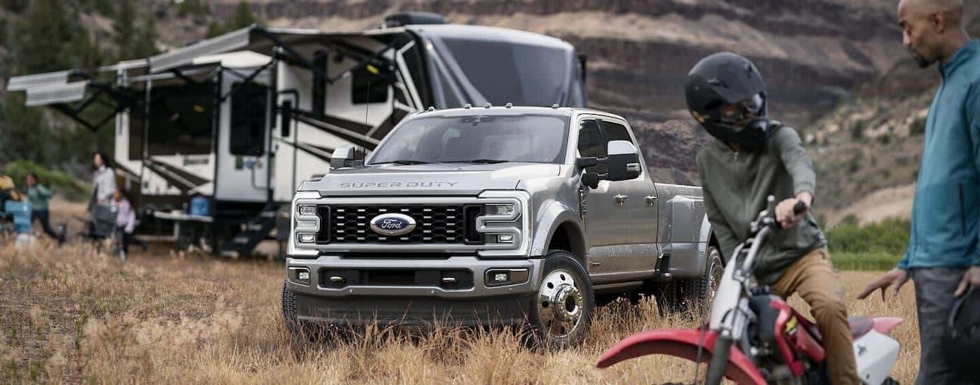 A grey 2024 Ford F-450 Super Duty is parked at a grassy campsite.