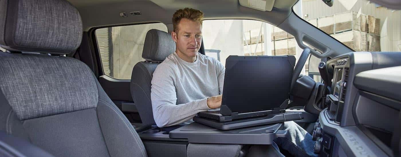 A man is using a laptop inside of a 2024 Ford F-350 Super Duty.