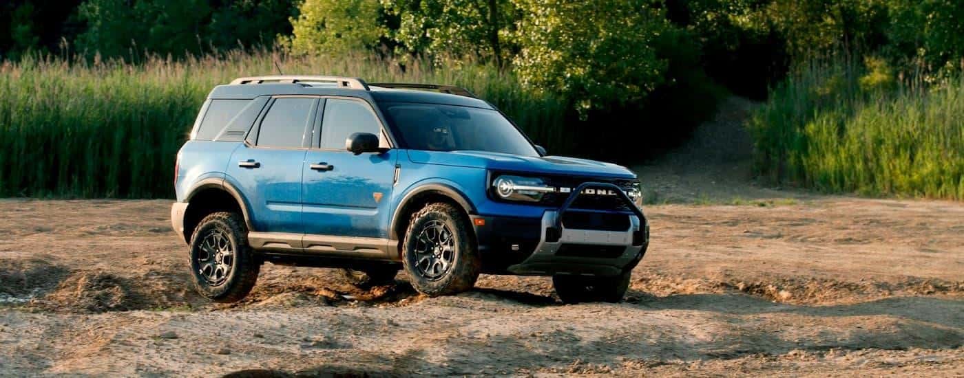 A blue 2025 Ford Bronco Sport Badlands is driving over a dirt path.