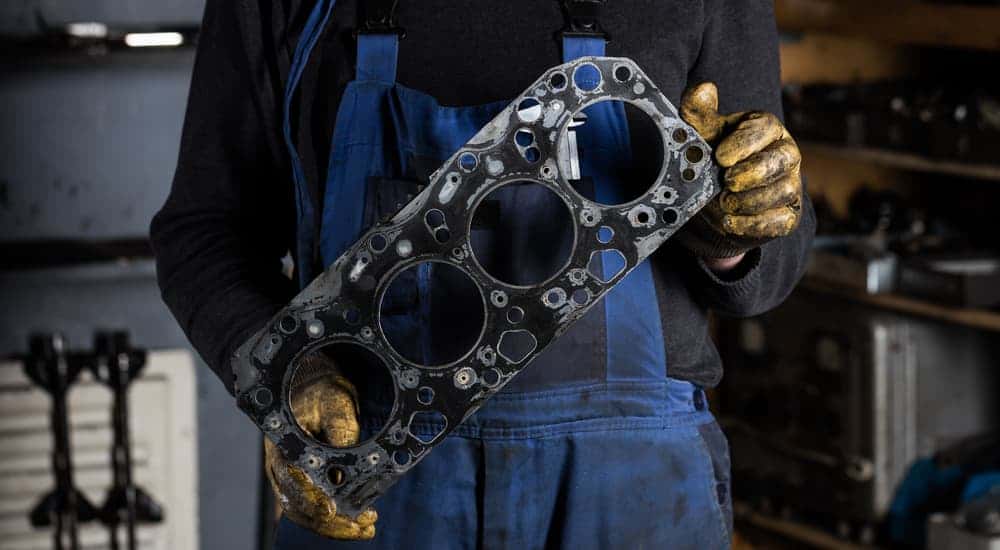 Close-up of a mechanic holding up a gasket during a head gasket repair.