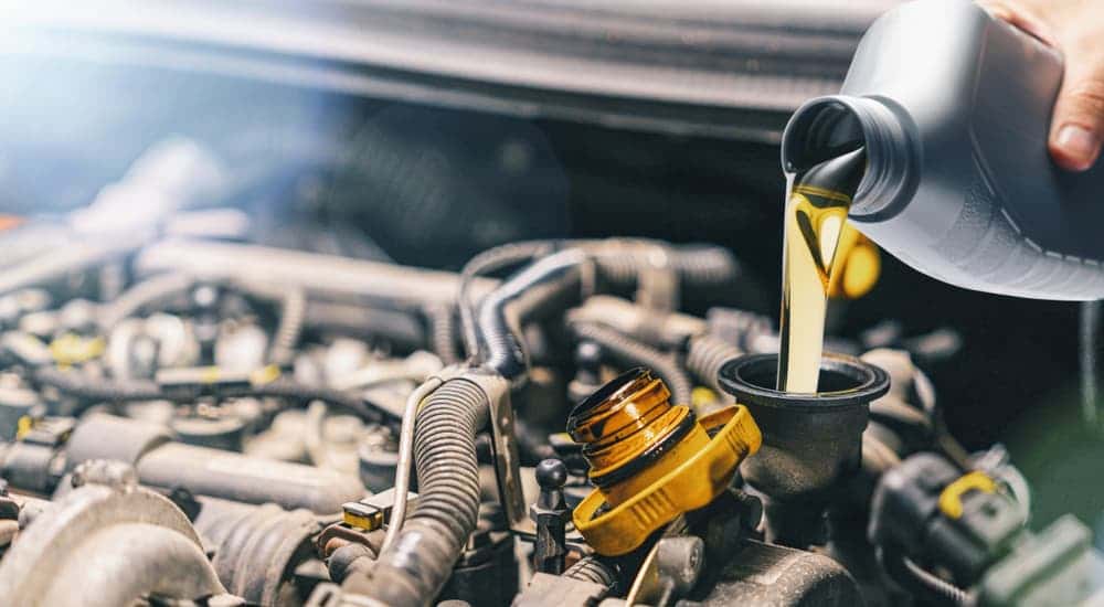 A can of oil being poured into an engine.