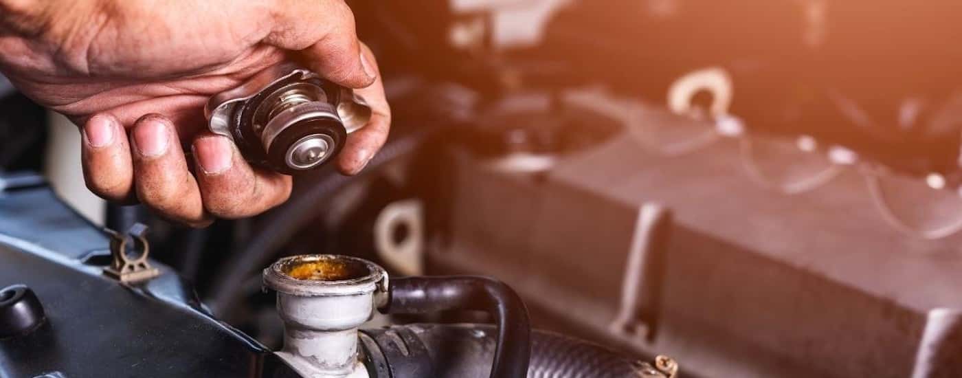 A close-up shows a mechanic removing a radiator cap.