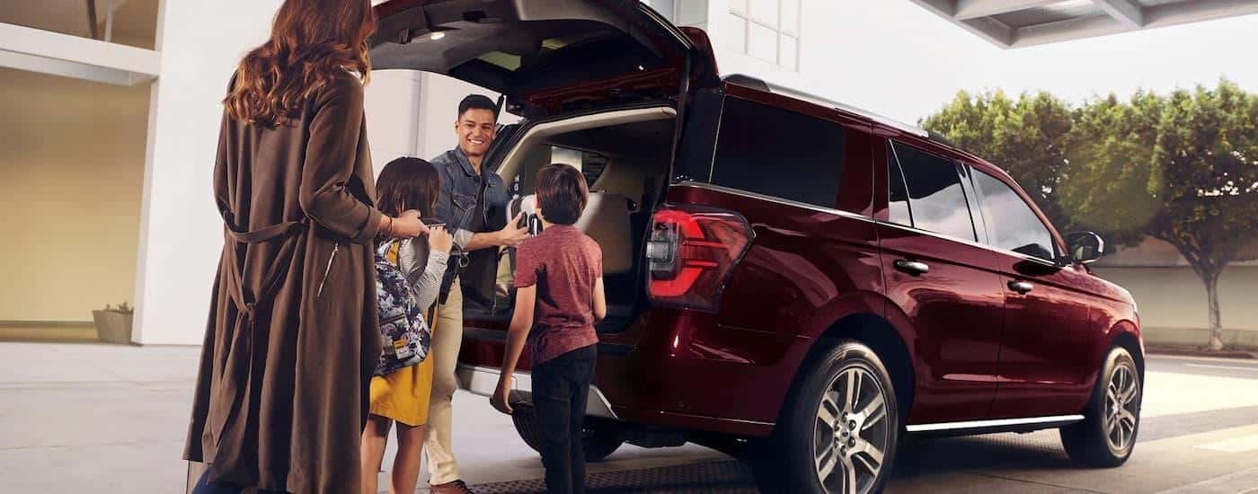 A family is shown putting cargo into the rear of a red 2023 Ford Expedition.