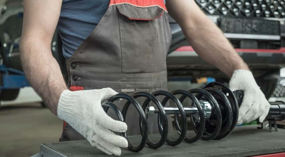 A mechanic holding a car strut.